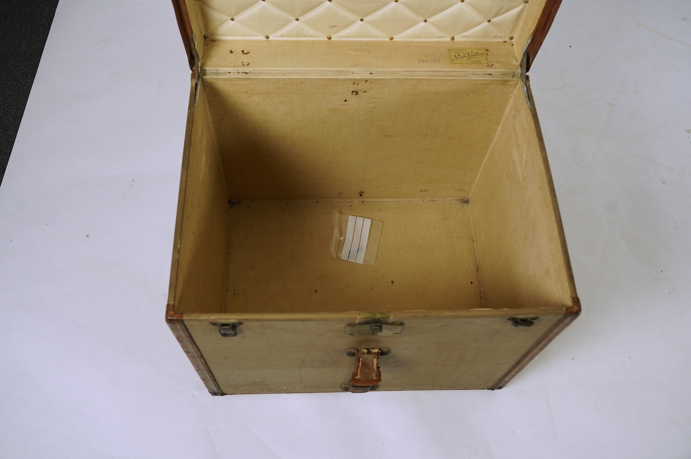 A vintage Louis Vuitton trunk, with brass and leather mounts and studded wooden slats, in plain beige canvas, with label for Paris and London, number 159008, 61cm wide, 48cm deep, 53cm high